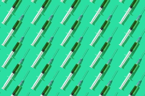 Multiple syringes organized in a pattern over green background stock photo