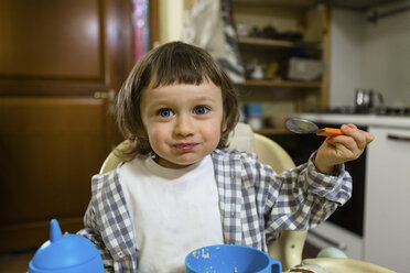 Portrait of cute toddler boy sitting in high chair in kitchen - MGIF00290