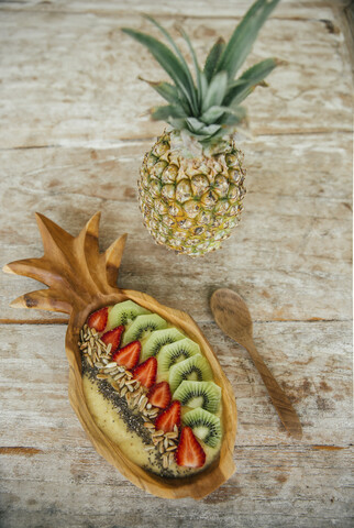 Smoothie Bowl mit Mango und Ananas garniert mit Kiwi, Erdbeeren, Chia und Sonnenblumenkernen, lizenzfreies Stockfoto