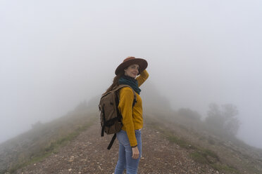 Frau beim Wandern im Nebel, stehend auf einem Bergpfad - AFVF02190