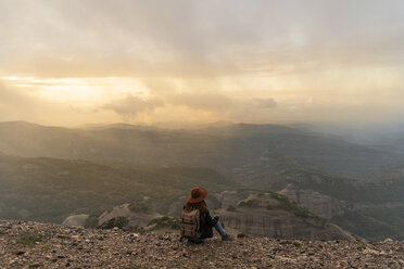 Frau mit Rucksack, auf einem Berg sitzend, mit Blick auf die Aussicht - AFVF02198