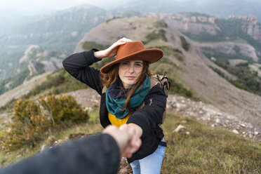 Frau mit Hut, auf einem Berg stehend, hält sich an der Hand eines Mannes fest - AFVF02199