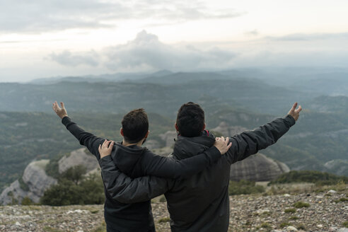 friends standing on mountain peak with arms around, enjoying he view - AFVF02203