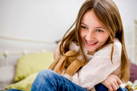 Porträt eines lächelnden Mädchens, das ein Stofftier kuschelt, lizenzfreies Stockfoto
