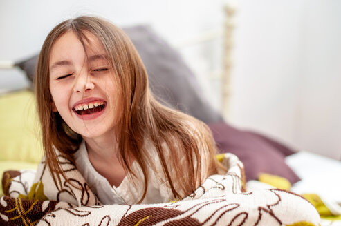 Portrait of laughing girl lying on bed - VWF00009