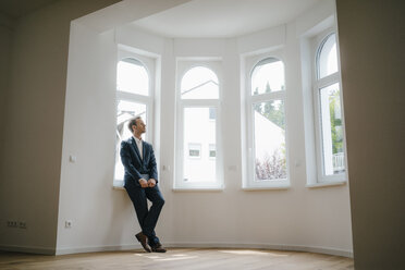 Estate agent waiting in newly refurbished home, holding laptop - KNSF05460