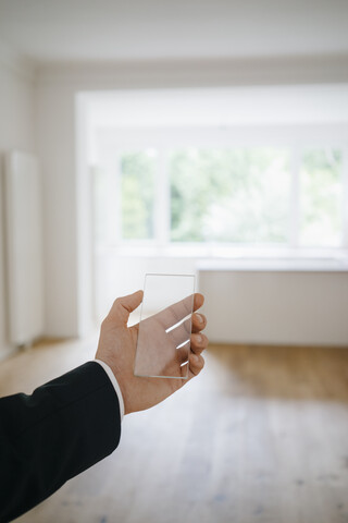 Hand hält Glas-Touchscreen in renoviertem Haus, lizenzfreies Stockfoto