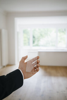 Hand hält Glas-Touchscreen in renoviertem Haus - KNSF05477