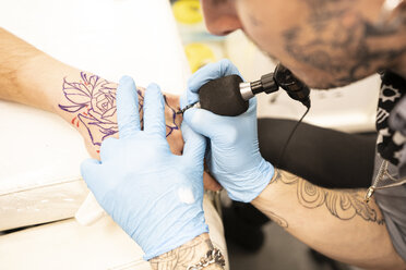 Tattoo artist tattoing hand - DAMF00024