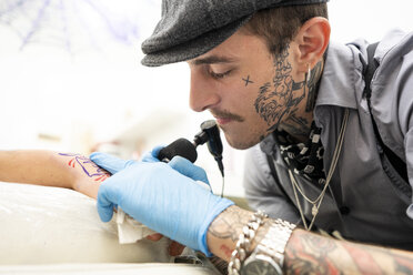 Tattoo artist tattoing hand - DAMF00025