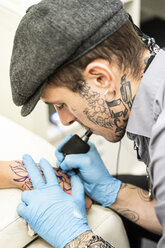 Tattoo artist tattoing hand - DAMF00027