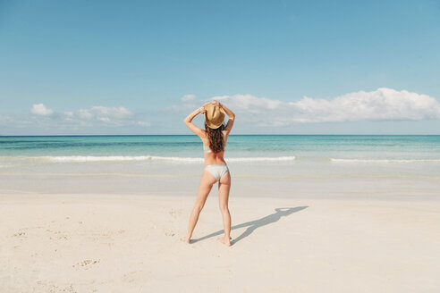 Spain, Mallorca, Rear view of a young woman on holidays standing on the beach - LOTF00001