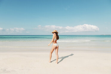 Spain, Mallorca, Rear view of a young woman on holidays standing on the beach - LOTF00002