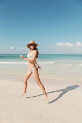 Spanien, Mallorca, Glückliche junge Frau im Urlaub, die an einem Sommertag am Strand springt - LOTF00003