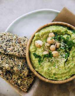 Erbsen-Hummus in Holzschale, Knäckebrot auf Teller - MBEF01462