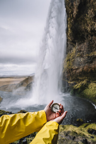 Island, Seljalandsfoss Wasserfall, Frauenhand hält Kompass, lizenzfreies Stockfoto