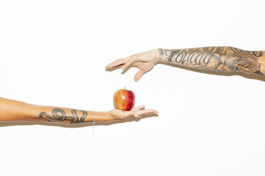 Die Hand einer Frau bietet einem Mann einen Apfel an - MRAF00354