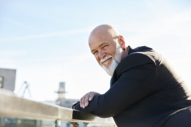 Elegant businessman standing in the city, leaning on railing, enjoying the view - RHF02435