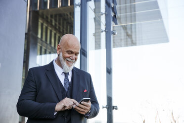 Eleganter Geschäftsmann mit Smartphone in der Stadt - RHF02440