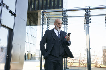 Elegant businessman using smartphone in the city - RHF02445