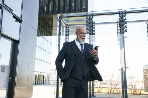 Eleganter Geschäftsmann mit Smartphone in der Stadt - RHF02445