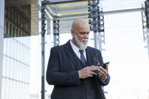 Elegant businessman using smartphone in the city - RHF02446