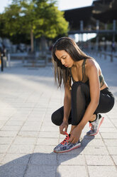 Junge Frau bindet ihre Schuhe vor dem Training - MAUF02149