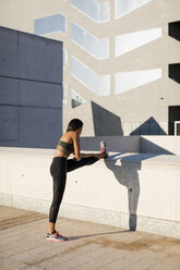 Young woman doing stretching exercise in the city - MAUF02159