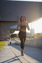 Young woman running in the city in sunlight - MAUF02169