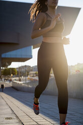 Young woman running in the city in sunlight - MAUF02170