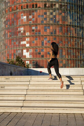 Young woman running up stairs in the city - MAUF02173