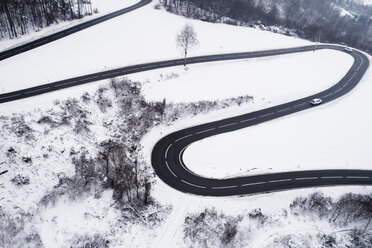 Austria, Wienerwald, cars driving on mountain road in snow-covered landscape, aerial view - HMEF00171