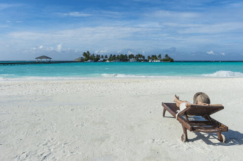 Malediven, Ari Atoll, Nalaguraidhoo, Sun Island Resort, Rückenansicht einer Frau beim Entspannen am Strand - RUNF00729