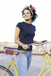 Glückliche junge Frau mit Fahrrad in der Stadt - ERRF00429