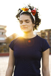 Portrait of young woman with closed eyes in the city at sunset - ERRF00434