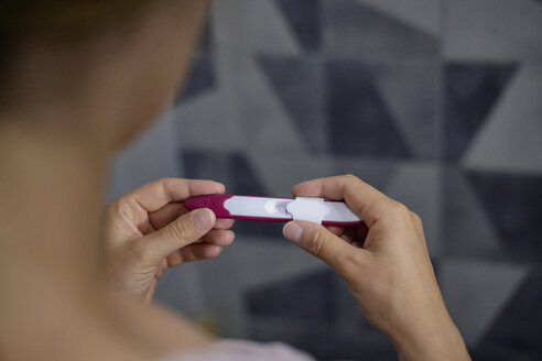 Close-up of woman checking her pregnancy test showing positive - BZF00478