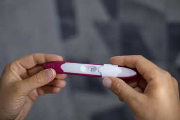 Nahaufnahme der Hände einer Frau, die einen positiven Schwangerschaftstest hält - BZF00479