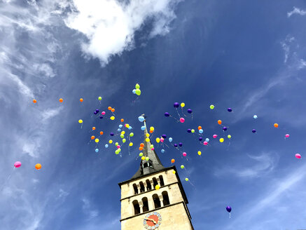 Deutschland, Sindelfingen, bunte Hochzeitsluftballons am Himmel über der Kirchturmspitze - MABF00513