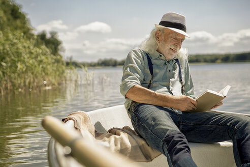 Porträt eines zufriedenen älteren Mannes, der in einem Ruderboot auf einem See sitzt und ein Buch liest - VWF00017