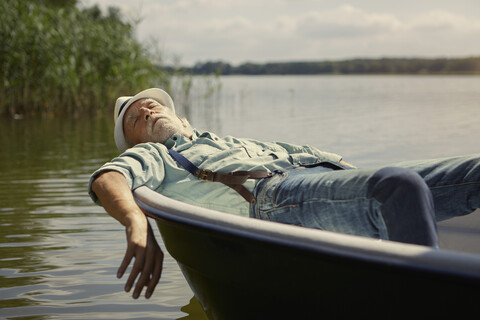 Senior man relaxing in rowing boat on a lake stock photo