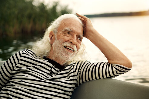 Porträt eines zufriedenen älteren Mannes mit weißen Haaren und Bart, der in einem Ruderboot auf einem See sitzt - VWF00020