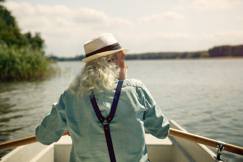 Rückenansicht eines älteren Mannes, der in einem Ruderboot auf einem See sitzt und Hosenträger und einen Sommerhut trägt - VWF00021