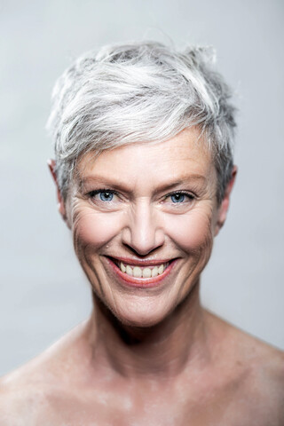 Portrait of laughing mature woman with short grey hair and blue eyes stock photo
