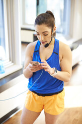 Fitness-Trainer wählt Musik vom Smartphone im Fitnessstudio aus - AURF08113