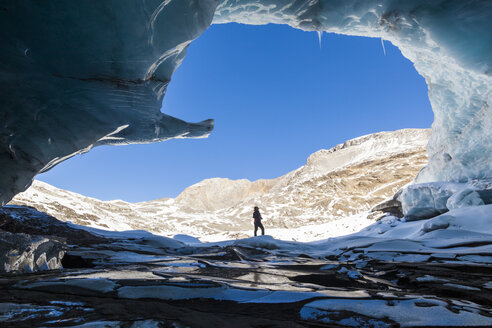 Frau betritt Eishöhle am Plaine Morte Gletscher, Kanton Bern, Schweiz - AURF08157