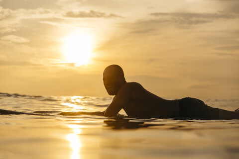 Surfer im Meer bei Sonnenuntergang, Changgu, Bali, Indonesien, lizenzfreies Stockfoto