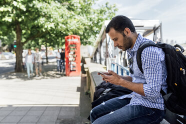 UK, London, Mann benutzt sein Smartphone auf der Straße - MGOF03902