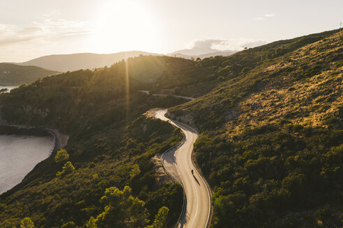 Italy, Elba Island, biker on coastal road against the sun, aerial view with drone - FBAF00216