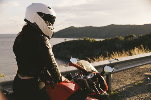 Italy, Elba Island, female motorcyclist at viewpoint stock photo