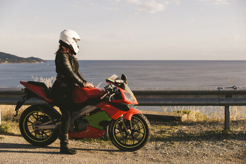 Italien, Insel Elba, Motorradfahrerin am Aussichtspunkt, lizenzfreies Stockfoto